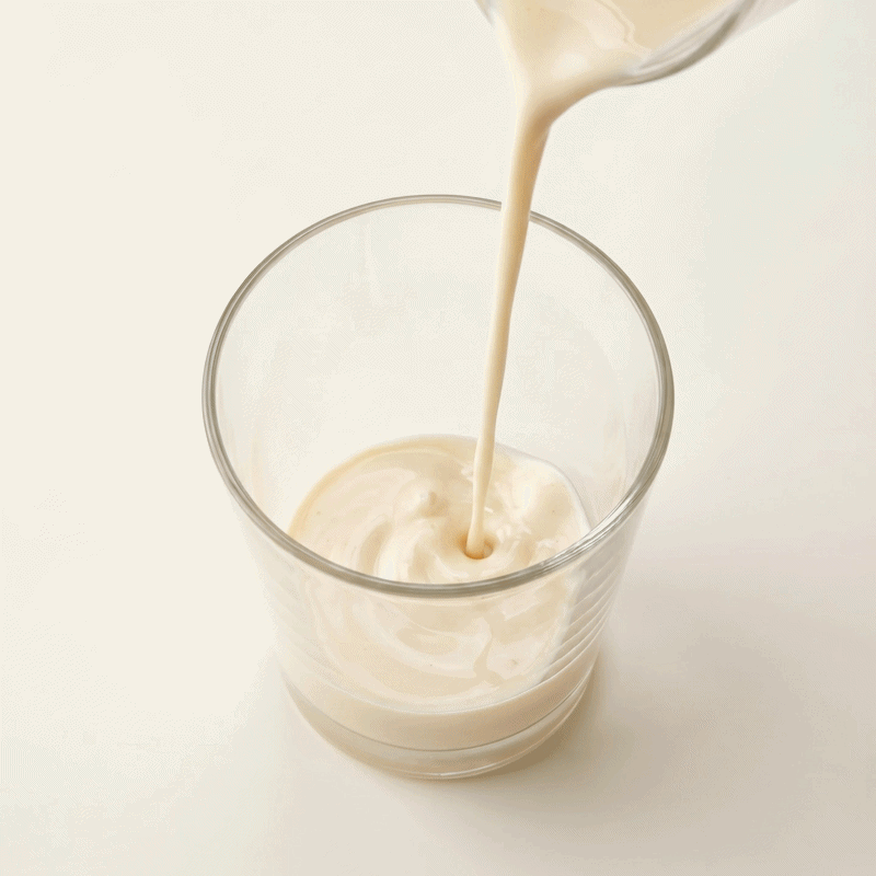 Cremiger Shake wird von oben in ein Glas gegossen.