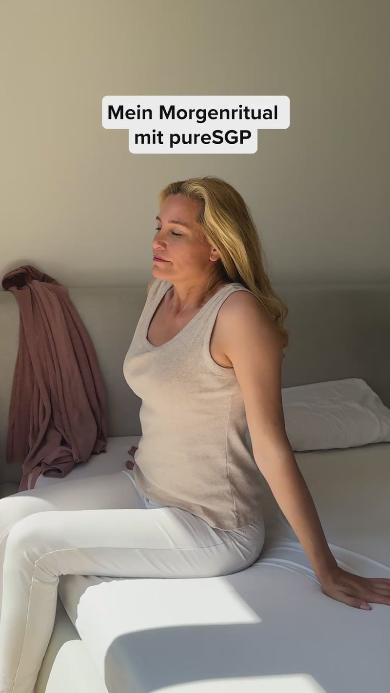 Mein Morgenritual mit pureSGP'. Eine Kundin zeigt, wie sie einen Löffel pureSGP Kollagenpulver in Wasser mischt. Sie erklärt, dass sie es nimmt, weil es ihrem Körper guttut, pharmazeutisch hergestellt und aus natürlichen Rohstoffen ohne Zusatzstoffe ist. Sie bewirbt es als 'Beauty-Booster'